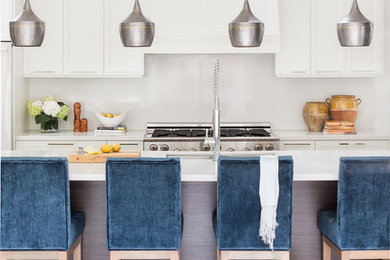 Example of a mid-sized trendy single-wall multicolored floor eat-in kitchen design in Vancouver with a double-bowl sink, shaker cabinets, white cabinets, solid surface countertops, white backsplash, stainless steel appliances, an island and white countertops
