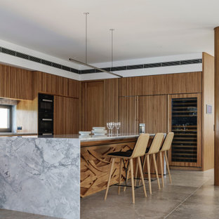 Photo of a contemporary u-shaped kitchen in Sydney with raised-panel cabinets, medium wood cabinets, marble benchtops, window splashback, panelled appliances, concrete floors, with island, grey floor and grey benchtop.