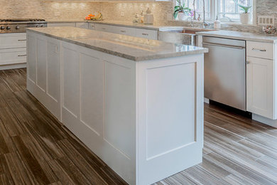 Example of a large transitional galley porcelain tile eat-in kitchen design in Chicago with a farmhouse sink, shaker cabinets, white cabinets, quartzite countertops, multicolored backsplash, glass sheet backsplash, stainless steel appliances and an island