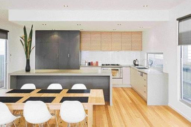 Small contemporary l-shaped open plan kitchen in Melbourne with a submerged sink, flat-panel cabinets, white cabinets, engineered stone countertops, white splashback, glass sheet splashback, stainless steel appliances, light hardwood flooring and an island.