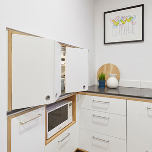 Photo of a large scandinavian galley kitchen pantry in Melbourne with a drop-in sink, beaded inset cabinets, medium wood cabinets, concrete benchtops, white splashback, subway tile splashback, stainless steel appliances, cork floors and with island.