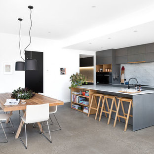 Mid-sized contemporary galley open plan kitchen in Melbourne with flat-panel cabinets, marble benchtops, marble splashback, black appliances, concrete floors, with island, grey floor, grey cabinets, white splashback and white benchtop.