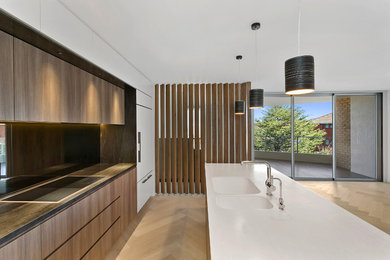 Offene, Mittelgroße Moderne Küche in L-Form mit integriertem Waschbecken, hellbraunen Holzschränken, Mineralwerkstoff-Arbeitsplatte, Rückwand aus Spiegelfliesen und hellem Holzboden in Sydney