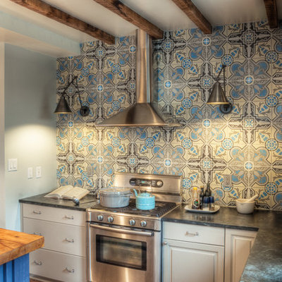 Elegant kitchen photo in Philadelphia with stainless steel appliances, an undermount sink, raised-panel cabinets, gray cabinets, soapstone countertops and blue backsplash
