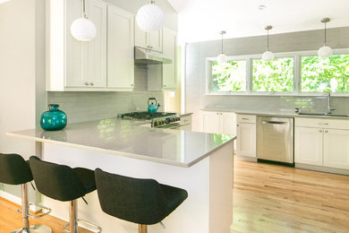 Mid-sized 1950s u-shaped light wood floor and brown floor eat-in kitchen photo in Atlanta with shaker cabinets, white cabinets, stainless steel appliances, a peninsula, gray countertops, ceramic backsplash, a double-bowl sink, gray backsplash and quartz countertops