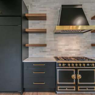 Aménagement d'une grand cuisine ouverte contemporaine en L avec un évier intégré, un placard à porte plane, des portes de placard noires, un plan de travail en marbre, une crédence grise, une crédence en marbre, un électroménager noir, un sol en bois brun, un îlot central, un sol marron et un plan de travail gris.
