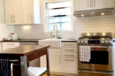 Small trendy light wood floor eat-in kitchen photo in Minneapolis with a farmhouse sink, shaker cabinets, white cabinets, laminate countertops, white backsplash, subway tile backsplash, stainless steel appliances and an island
