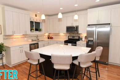 Huge trendy l-shaped medium tone wood floor and multicolored floor kitchen pantry photo in Chicago with a drop-in sink, flat-panel cabinets, light wood cabinets, quartz countertops, white backsplash, ceramic backsplash, stainless steel appliances, an island and white countertops