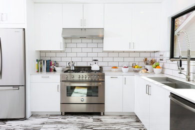 Example of a mid-sized trendy l-shaped porcelain tile enclosed kitchen design in Dallas with flat-panel cabinets, white backsplash, stainless steel appliances, white cabinets, subway tile backsplash, an undermount sink, quartzite countertops and an island