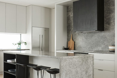 Exempel på ett modernt grå grått l-kök, med släta luckor, vita skåp, grått stänkskydd, stänkskydd i sten, rostfria vitvaror, ljust trägolv, en köksö och beiget golv