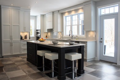Example of a mid-sized transitional l-shaped concrete floor and gray floor open concept kitchen design in Montreal with an undermount sink, shaker cabinets, white cabinets, quartz countertops, white backsplash, glass tile backsplash, stainless steel appliances and an island