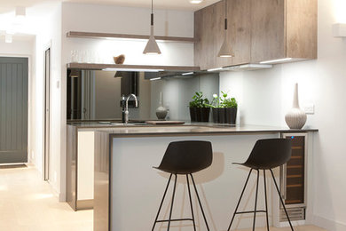 На фото: кухня в скандинавском стиле с обеденным столом, плоскими фасадами, светлыми деревянными фасадами, светлым паркетным полом и барной стойкой