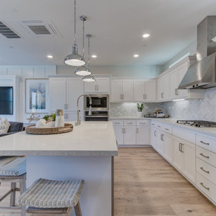 Open concept kitchen pictures - Example of a l-shaped open concept kitchen design in San Francisco with an undermount sink, recessed-panel cabinets, white cabinets, stainless steel appliances and an island