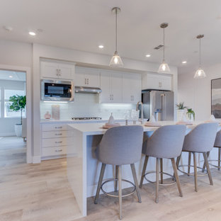 Open concept kitchen designs - Example of a single-wall open concept kitchen design in San Francisco with an undermount sink, recessed-panel cabinets, stainless steel appliances and an island