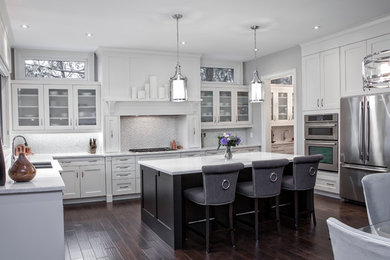 Inspiration for a large transitional u-shaped dark wood floor eat-in kitchen remodel in Toronto with an undermount sink, shaker cabinets, white cabinets, marble countertops, white backsplash, glass tile backsplash, stainless steel appliances and an island