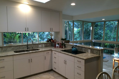 Photo of a large classic l-shaped kitchen/diner in Hawaii with a double-bowl sink, flat-panel cabinets, white cabinets, granite worktops, beige splashback, stone slab splashback, stainless steel appliances, ceramic flooring, a breakfast bar, beige floors and beige worktops.