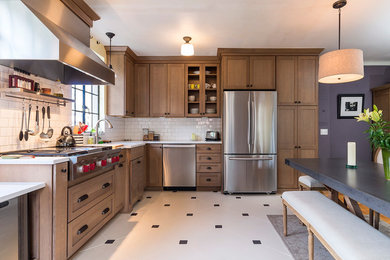 ポートランドにあるトラディショナルスタイルのおしゃれなダイニングキッチン (シェーカースタイル扉のキャビネット、中間色木目調キャビネット、白いキッチンパネル、サブウェイタイルのキッチンパネル、シルバーの調理設備) の写真
