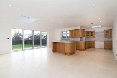 Large contemporary l-shaped kitchen/diner in London with shaker cabinets, light wood cabinets, granite worktops, porcelain flooring, an island and beige floors.