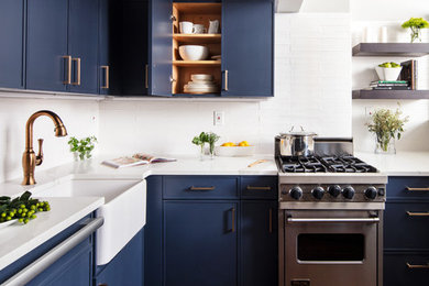 Small trendy dark wood floor and brown floor kitchen photo in New York with a farmhouse sink, blue cabinets, white backsplash, stainless steel appliances, white countertops, flat-panel cabinets, quartzite countertops, subway tile backsplash and no island