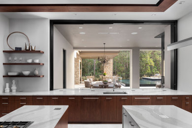 Cette image montre une très grande cuisine minimaliste en bois brun avec un placard à porte plane, un plan de travail en quartz et un plan de travail blanc.