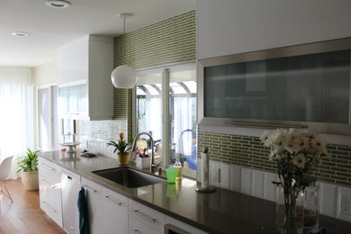 Inspiration for a mid-sized transitional single-wall light wood floor and brown floor enclosed kitchen remodel in San Diego with an undermount sink, flat-panel cabinets, white cabinets, solid surface countertops, green backsplash, mosaic tile backsplash, stainless steel appliances and no island