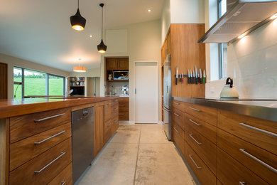 Foto de cocina comedor lineal campestre con puertas de armario de madera oscura, encimera de acero inoxidable, suelo de cemento y una isla