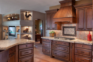 Open concept kitchen - large traditional l-shaped light wood floor open concept kitchen idea in Phoenix with a farmhouse sink, raised-panel cabinets, medium tone wood cabinets, granite countertops, multicolored backsplash, mosaic tile backsplash, paneled appliances and an island