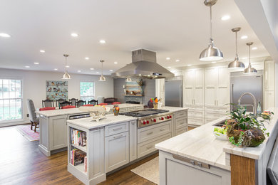 Example of a large transitional single-wall medium tone wood floor and brown floor eat-in kitchen design in Other with an undermount sink, shaker cabinets, white cabinets, marble countertops, multicolored backsplash, matchstick tile backsplash, stainless steel appliances and two islands