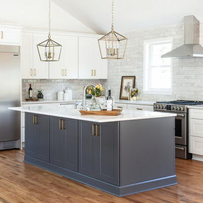 Inspiration for a large transitional l-shaped brown floor and medium tone wood floor kitchen remodel in Nashville with shaker cabinets, white cabinets, quartz countertops, gray backsplash, subway tile backsplash, stainless steel appliances, an island and white countertops