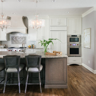 This is an example of a large traditional l-shaped open plan kitchen in Atlanta with a farmhouse sink, stainless steel appliances, with island, brown floor, flat-panel cabinets, grey cabinets, granite benchtops, multi-coloured splashback, glass tile splashback, medium hardwood floors and beige benchtop.