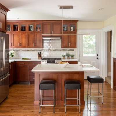 Kitchen - mid-sized craftsman l-shaped medium tone wood floor and brown floor kitchen idea in Boston with an undermount sink, shaker cabinets, medium tone wood cabinets, quartz countertops, white backsplash, subway tile backsplash, stainless steel appliances, an island and white countertops
