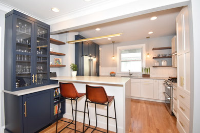 Mid-sized trendy u-shaped medium tone wood floor and brown floor eat-in kitchen photo in Chicago with shaker cabinets, blue cabinets, quartz countertops, white backsplash, ceramic backsplash, stainless steel appliances, a peninsula and gray countertops