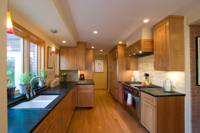 シカゴにある中くらいなトランジショナルスタイルのおしゃれなII型キッチン (ダブルシンク、レイズドパネル扉のキャビネット、中間色木目調キャビネット、ベージュキッチンパネル、シルバーの調理設備、無垢フローリング、アイランドなし、茶色い床) の写真