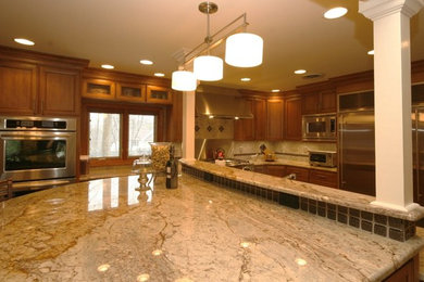他の地域にある広いコンテンポラリースタイルのおしゃれなキッチン (中間色木目調キャビネット、ベージュキッチンパネル、シルバーの調理設備) の写真