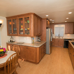 This is an example of a traditional eat-in kitchen in Other with an undermount sink, shaker cabinets, medium wood cabinets, quartz benchtops, beige splashback, subway tile splashback, black appliances, vinyl floors and no island.