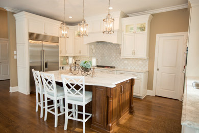 Eat-in kitchen - large traditional u-shaped medium tone wood floor and brown floor eat-in kitchen idea in Chicago with an undermount sink, raised-panel cabinets, white cabinets, marble countertops, gray backsplash, cement tile backsplash, stainless steel appliances, an island and white countertops