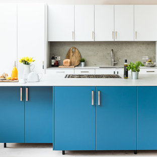 Inspiration for a large contemporary kitchen in London with an integrated sink, flat-panel cabinets, turquoise cabinets, concrete benchtops, grey splashback, slate splashback, stainless steel appliances, light hardwood floors, with island and grey floor.