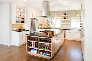Example of a mid-sized trendy u-shaped medium tone wood floor eat-in kitchen design in San Francisco with flat-panel cabinets, white cabinets, quartzite countertops, beige backsplash, an island, matchstick tile backsplash, stainless steel appliances and an undermount sink