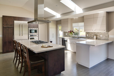 Eat-in kitchen - large modern u-shaped medium tone wood floor and gray floor eat-in kitchen idea in San Francisco with an island, an undermount sink, flat-panel cabinets, white cabinets, granite countertops, gray backsplash, glass tile backsplash and stainless steel appliances