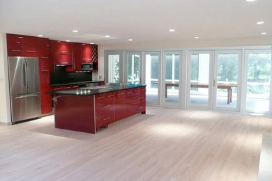 Mid-sized trendy light wood floor kitchen photo in Other with an undermount sink, flat-panel cabinets, red cabinets, black backsplash, stainless steel appliances and an island