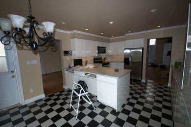 Foto på ett mellanstort funkis kök, med en enkel diskho, vita skåp, beige stänkskydd, stänkskydd i keramik, rostfria vitvaror, klinkergolv i keramik och en köksö