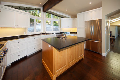 Design ideas for a medium sized traditional u-shaped open plan kitchen in Vancouver with a submerged sink, recessed-panel cabinets, white cabinets, tile countertops, beige splashback, dark hardwood flooring, an island and brown floors.