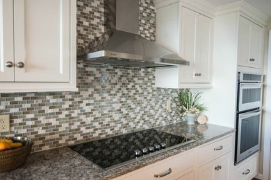 Kitchen - mid-sized coastal u-shaped dark wood floor and brown floor kitchen idea in Providence with shaker cabinets, white cabinets, granite countertops, gray backsplash, glass tile backsplash, stainless steel appliances and a peninsula
