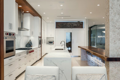 Open concept kitchen - large contemporary single-wall limestone floor and beige floor open concept kitchen idea in Miami with an undermount sink, flat-panel cabinets, white cabinets, marble countertops, white backsplash, marble backsplash, paneled appliances and two islands