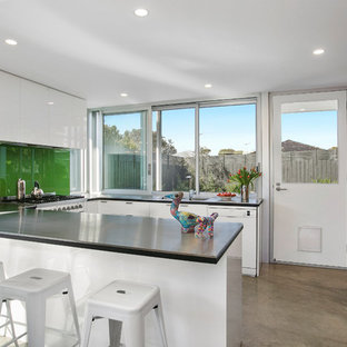 Design ideas for a contemporary u-shaped eat-in kitchen in Other with a drop-in sink, white cabinets, green splashback, glass sheet splashback, no island, grey benchtop, flat-panel cabinets, zinc benchtops and stainless steel appliances.