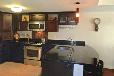 Photo of a small traditional u-shaped kitchen/diner in Boston with a submerged sink, recessed-panel cabinets, medium wood cabinets, granite worktops, black splashback, stone slab splashback, stainless steel appliances and medium hardwood flooring.