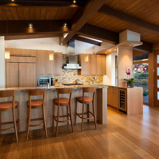 Exemple d'une cuisine ouverte linéaire moderne de taille moyenne avec un évier 1 bac, un placard à porte plane, des portes de placard en bois clair, un plan de travail en granite, une crédence multicolore, une crédence en carreau de verre, un électroménager encastrable, un sol en bambou et un îlot central.