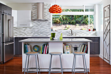 Trendy kitchen photo in Other with flat-panel cabinets, white cabinets, multicolored backsplash, stainless steel appliances and an island