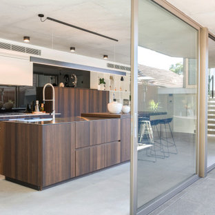 Inspiration for a large contemporary l-shaped eat-in kitchen in Sydney with an undermount sink, flat-panel cabinets, medium wood cabinets, black splashback, glass sheet splashback, panelled appliances, porcelain floors, with island, grey floor and beige benchtop.