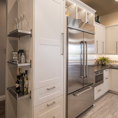 Example of a mid-sized transitional u-shaped porcelain tile open concept kitchen design in Phoenix with a farmhouse sink, shaker cabinets, white cabinets, solid surface countertops, white backsplash, subway tile backsplash, stainless steel appliances and an island